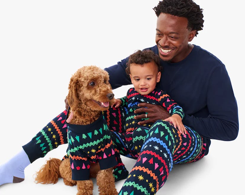 Dad, baby, and dog in matching Christmas pajamas