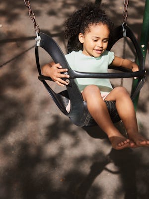 A smiling girl swings on a playground.
