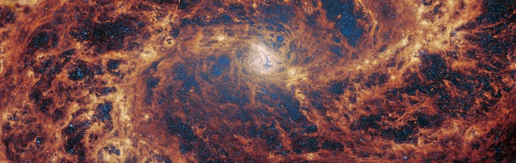 photo of a galaxy; a scaffolding of yellow and orange spirals outward on a black background