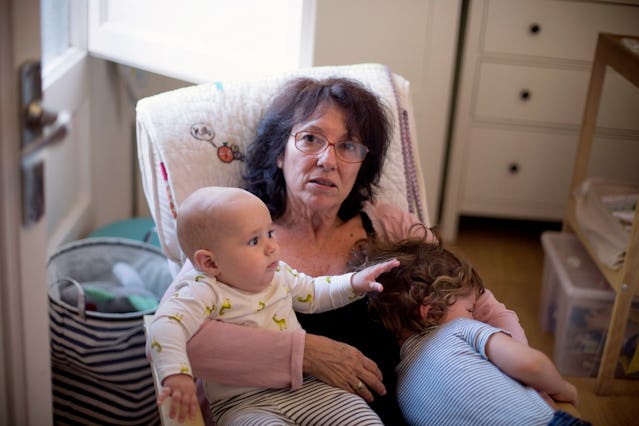 A grandma sits with her two grandkids in a rocking chair.