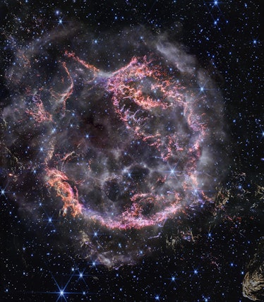 photo of a cloud of orange and magenta gas filaments forming nearly a perfect circle in space