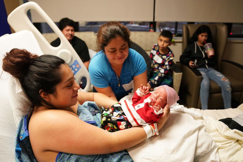 A baby born on Christmas day is handed to his mother. 