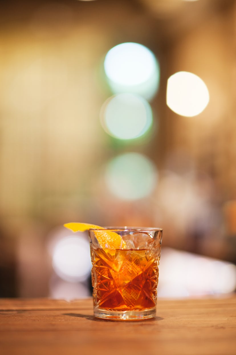 An Old Fashioned Cocktail with Scotch in a glass with an orange peel twist