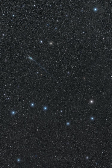 Photo of a faint green comet in a starry sky