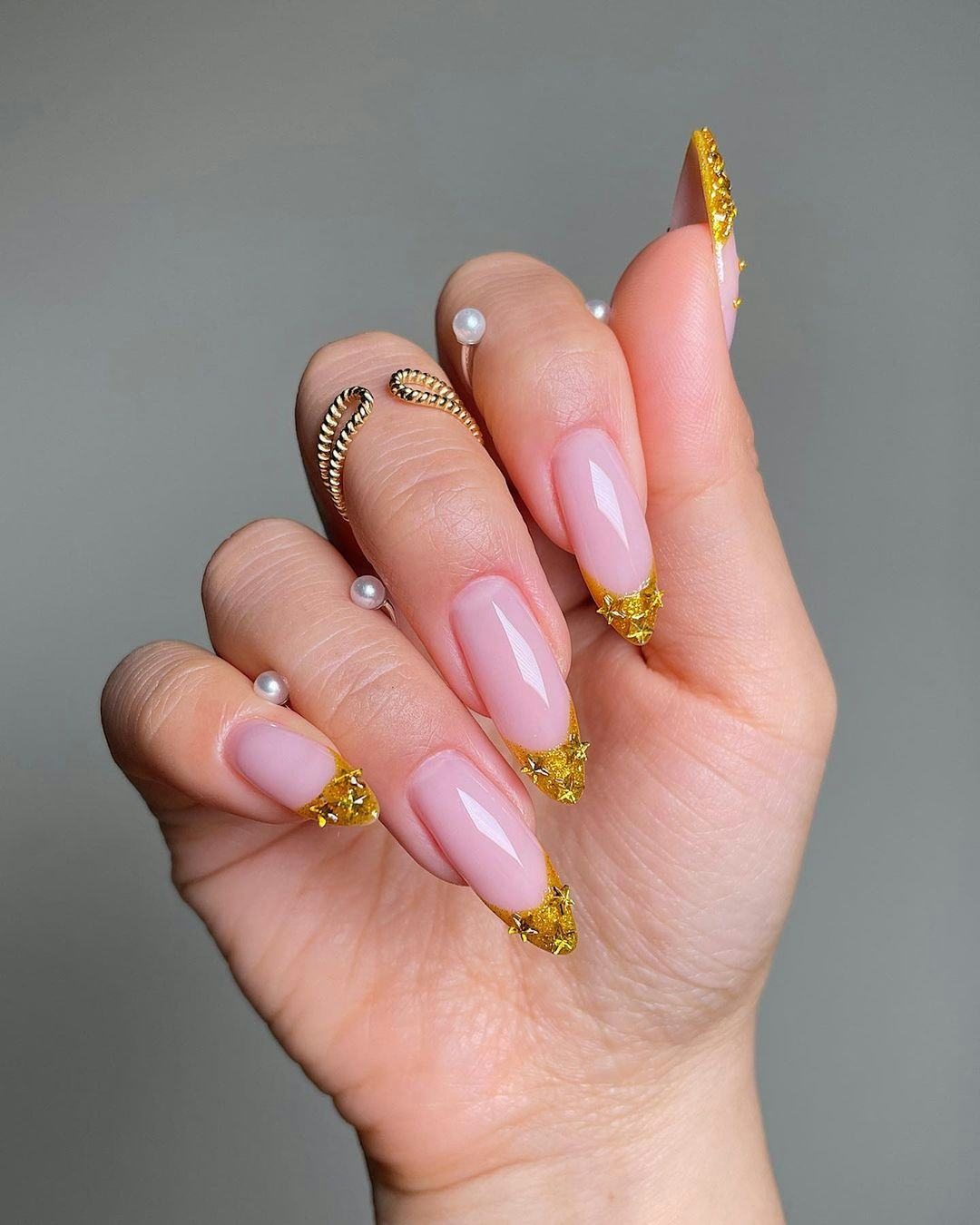 Gold French tip nails with stars are an on-trend manicure idea for New Year&rsquo;s Eve 2023 nails.