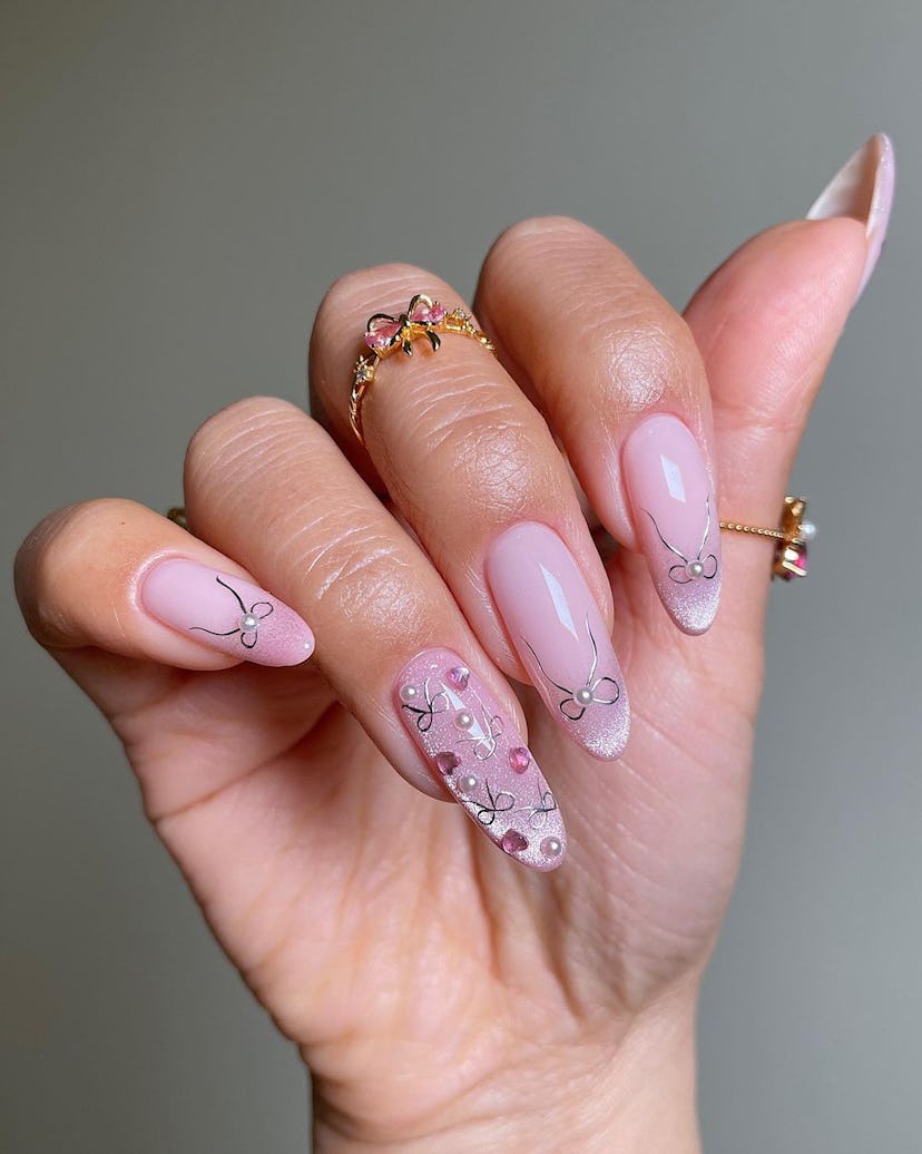 Sheer pink nails with silver coquette ribbon nail art is a simple manicure design idea for New Year'...