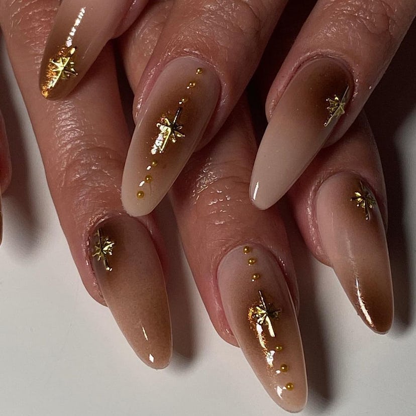 Brown aura nails with gold glitter are an on-trend Capricorn nail design idea for 2024.