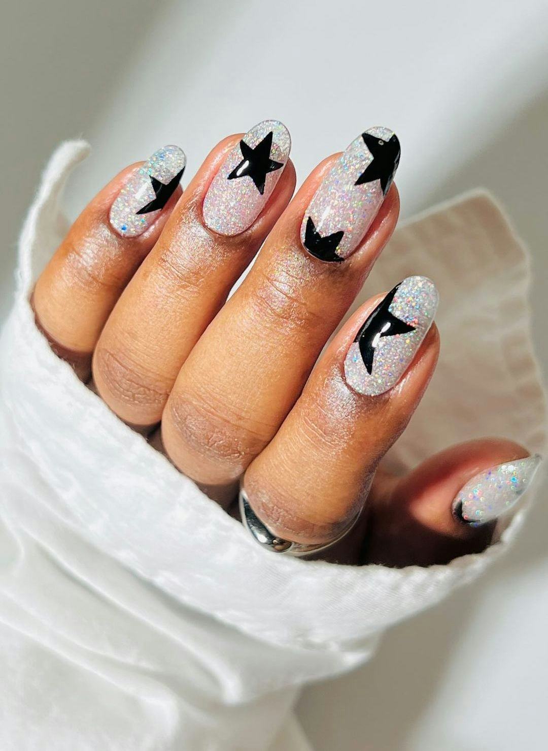 Silver glitter nails with black star nail art is a trendy manicure design idea for short almond New &hellip;