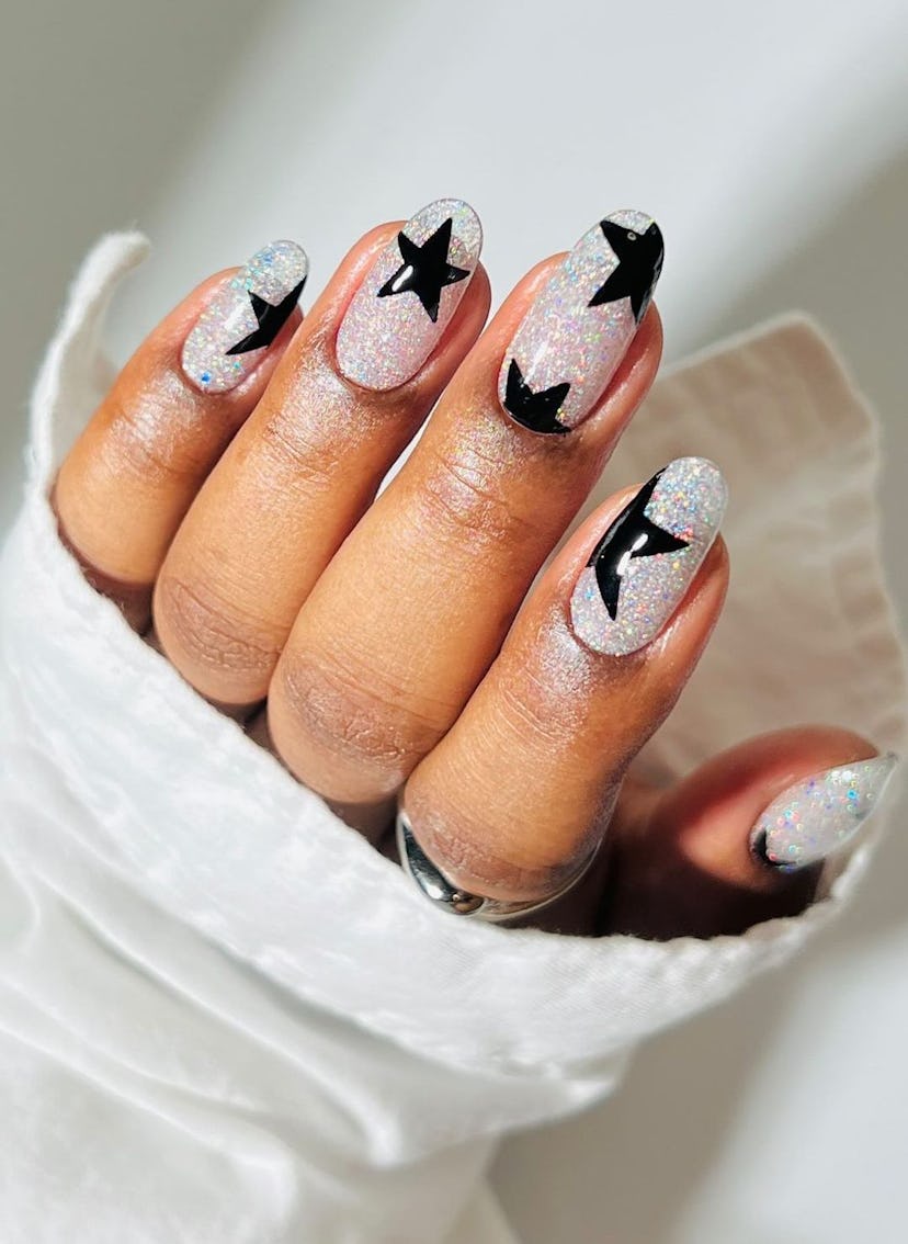 Silver glitter nails with black star nail art is a trendy manicure design idea for short almond New ...