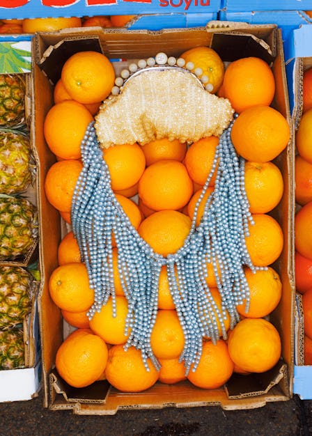 A sequined Gucci evening bag resting in a box of oranges. 