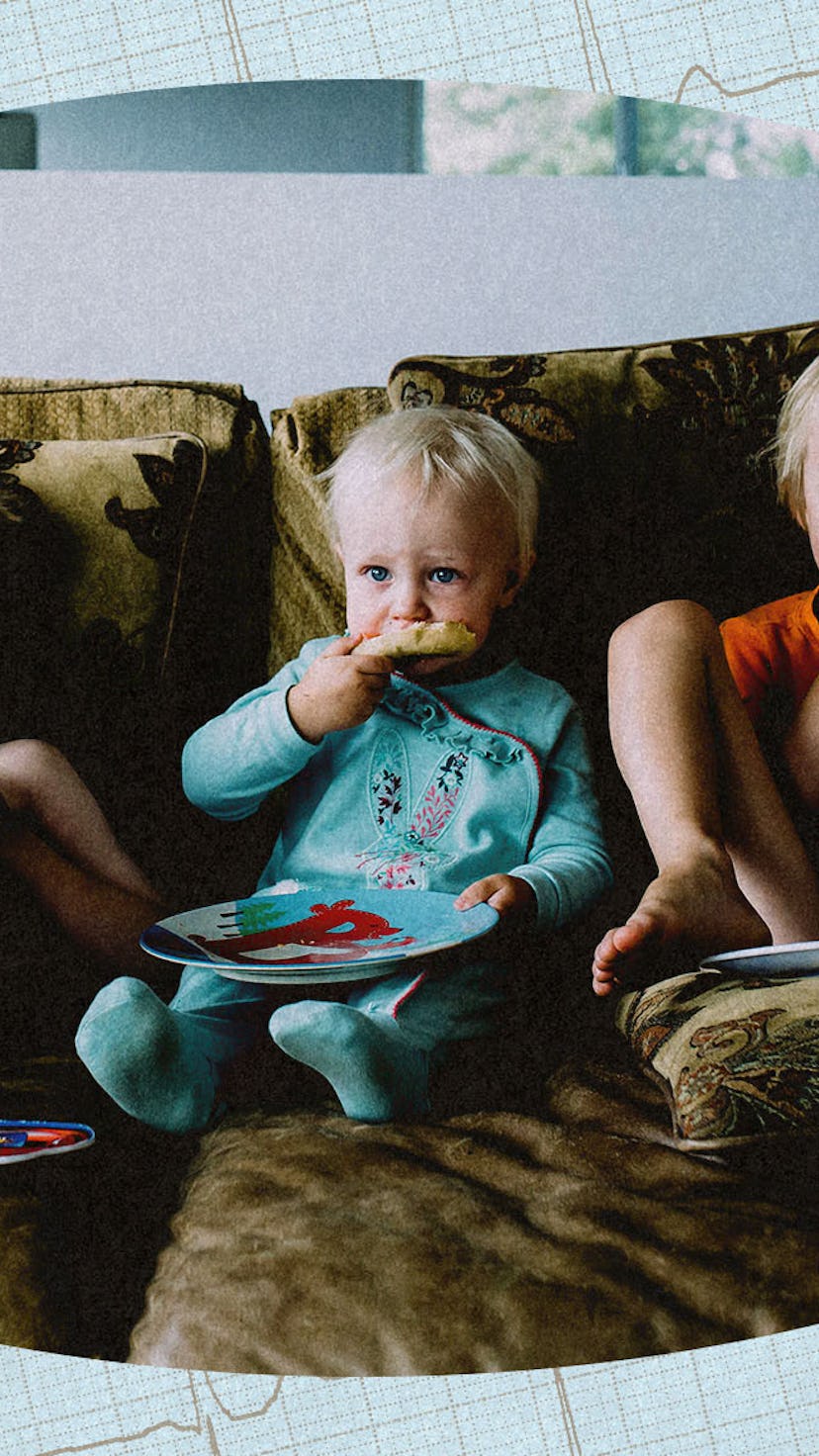Three children sitting on a couch, eating pizza and watching TV,