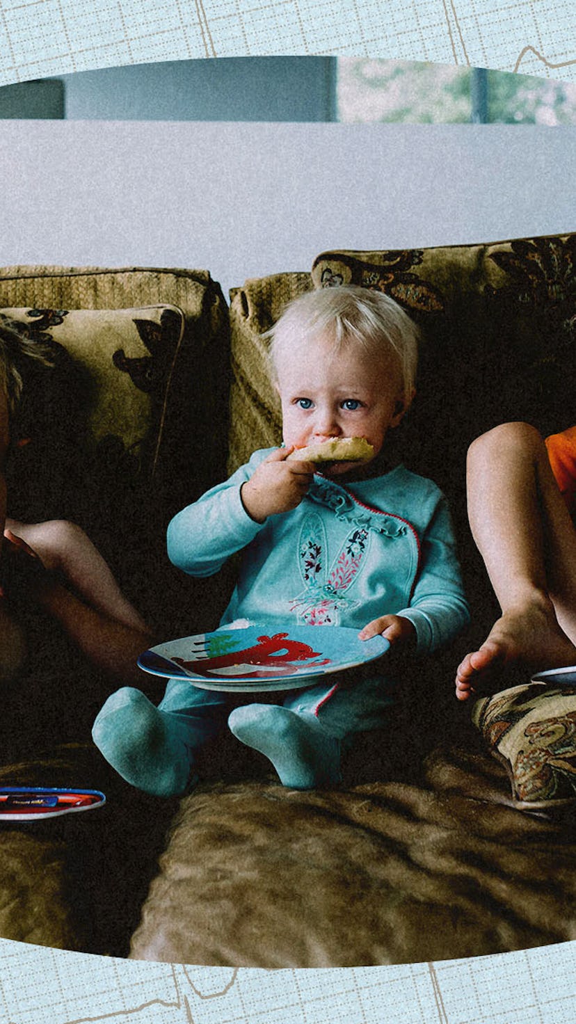 Three children sitting on a couch, eating pizza and watching TV,
