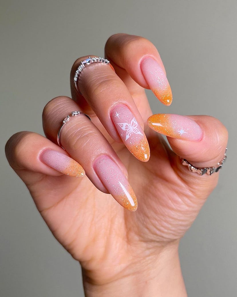 Glittering peach-colored French tip nails are an on-trend peach fuzz nail design for 2024.