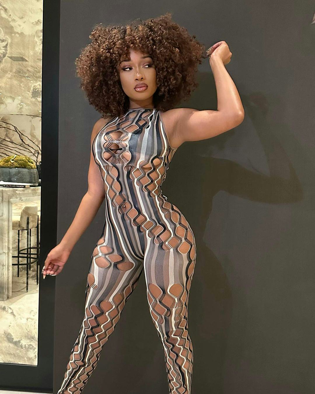 Megan Thee Stallion wears a printed catsuit with multiple cut-outs.