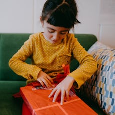 A young girl opens a Christmas present.