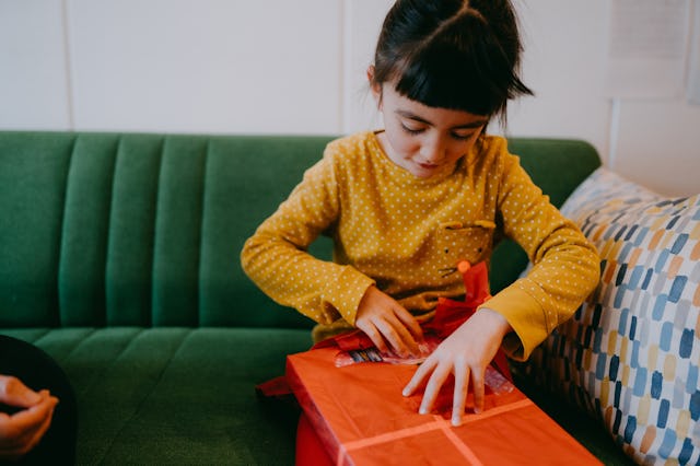 A young girl opens a Christmas present.