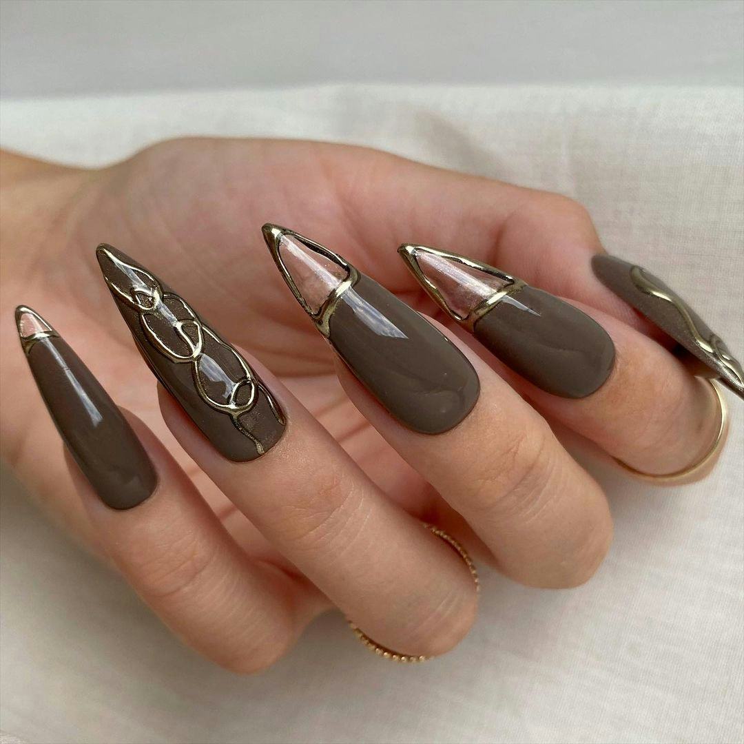 Muted brown stiletto nails with clear cut-outs are an on-trend Capricorn nail design for 2024.
