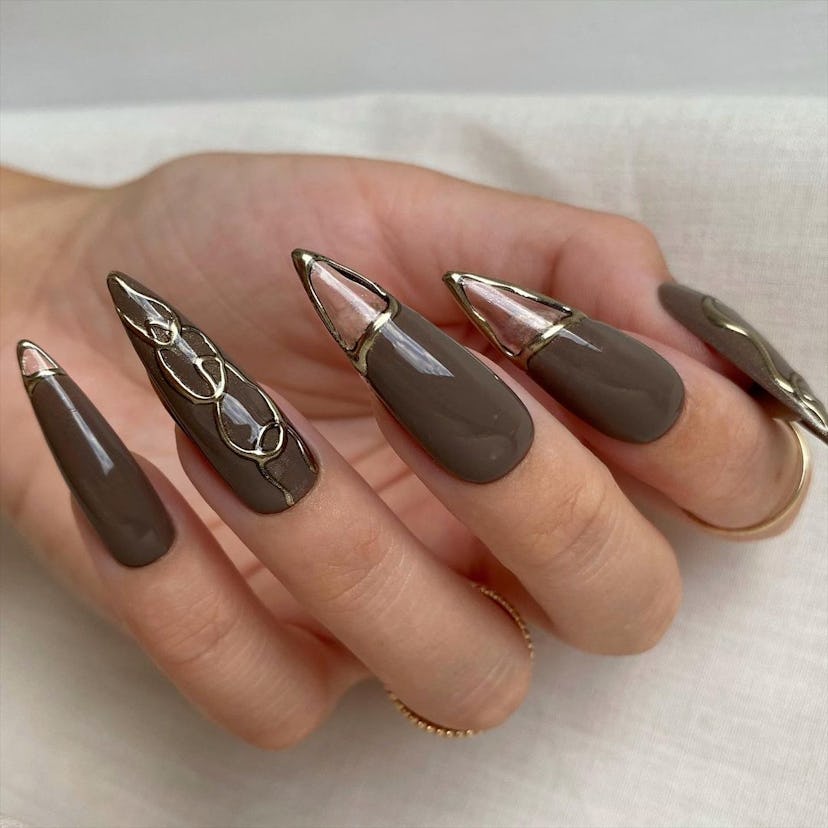 Muted brown stiletto nails with clear cut-outs are an on-trend Capricorn nail design for 2024.