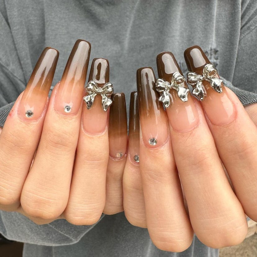 Chocolate nails with 3D silver ribbons are an on-trend Capricorn nail design for 2024.