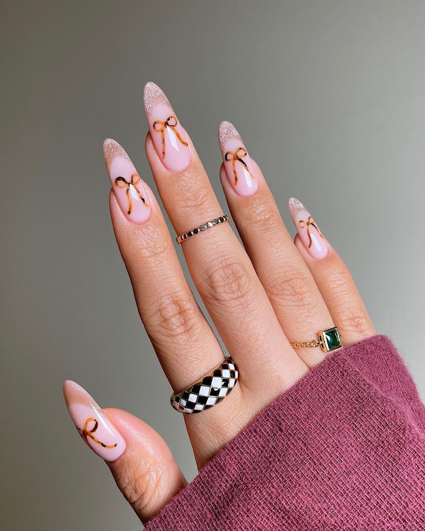 Tortoiseshell printed ribbons on brown French tip nails are an on-trend Capricorn nail design idea f...