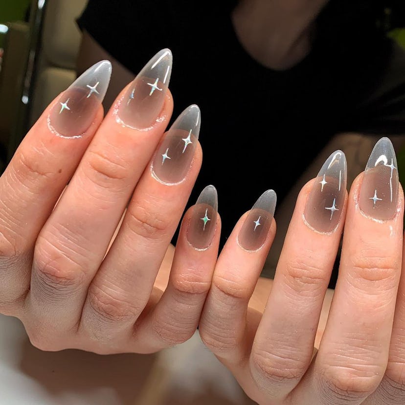 Sheer grey polish with celestial stars are an on-trend Capricorn nail design for 2024.