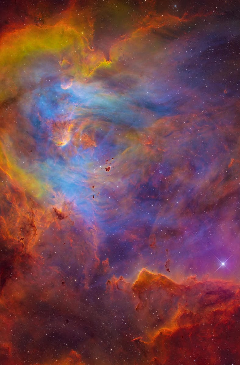 Thick dust and gas clouds outline a nebula. Wispy, less-dense clouds fill the center. They appear i...