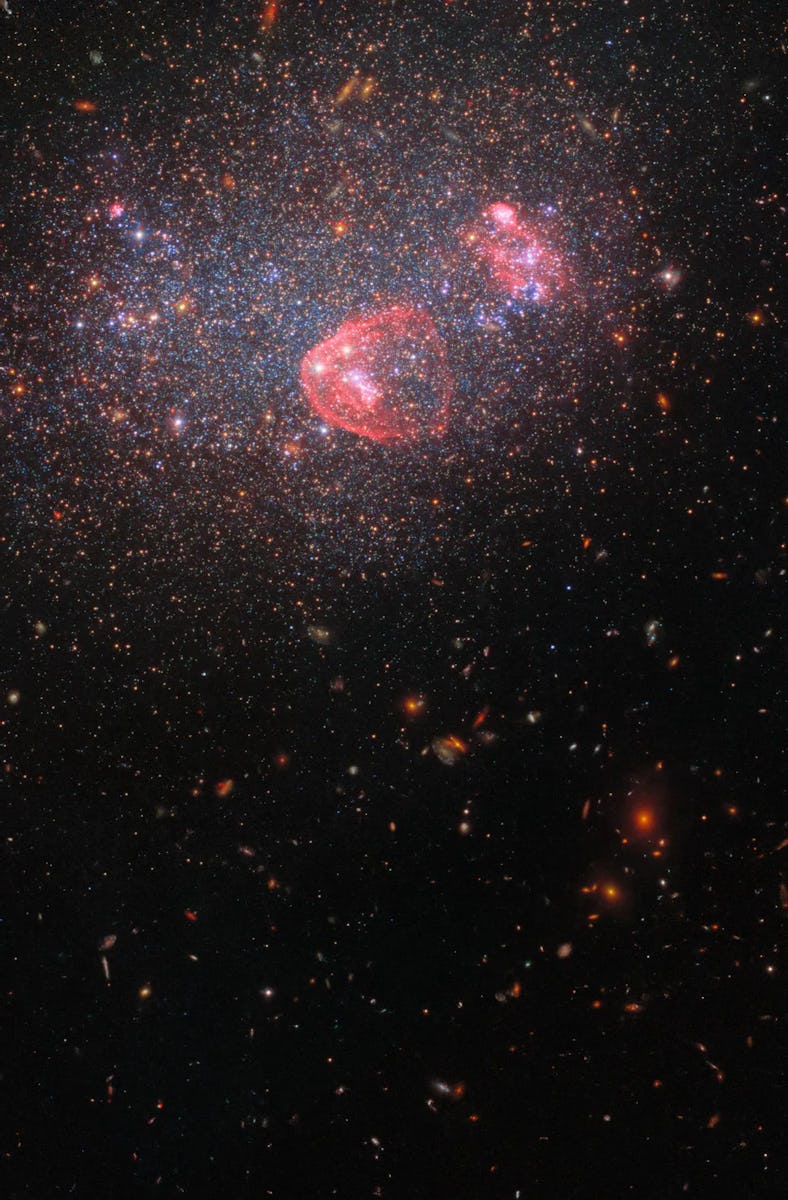 A deep space image showing two colorful, interacting galaxies amidst a field of stars.