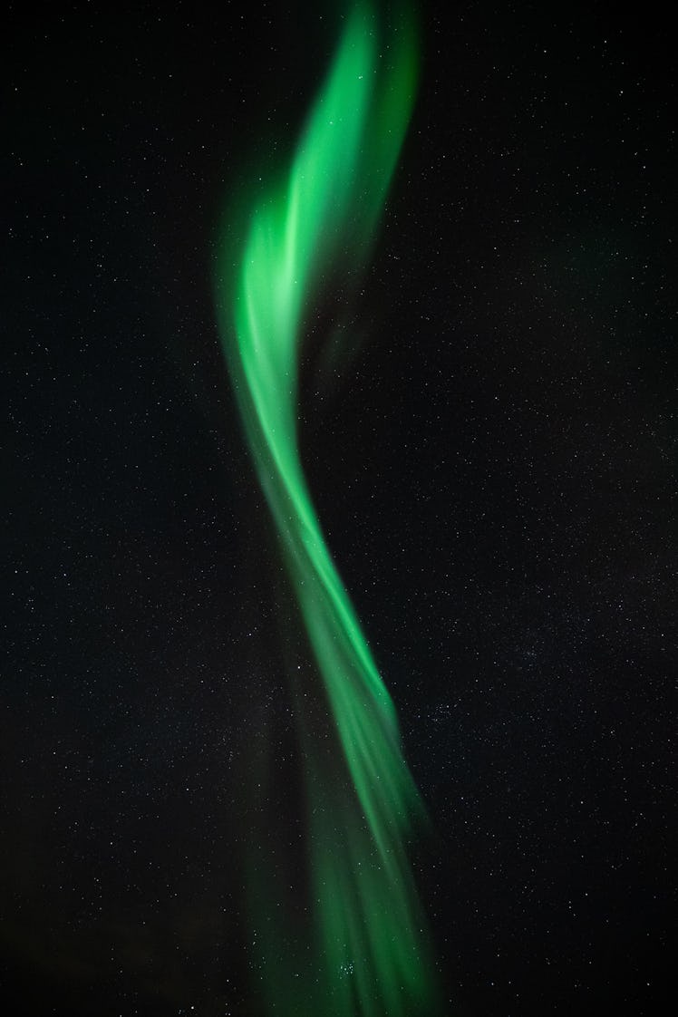 A strand of aurora borealis travels vertically. It looks twisted. The aurora band is also bent sligh...