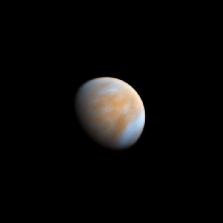 Venus is alone against the dark backdrop of space. It’s clouds appear as contrasting tones, and a sm...