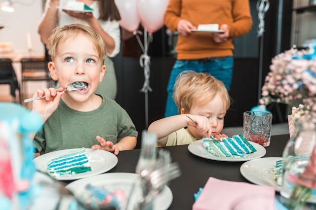 Two little boys eat cake at a birthday party. 