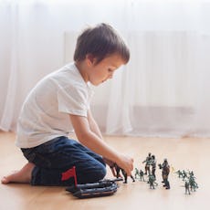 A little boy plays with action figures.