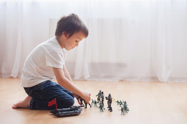 A little boy plays with action figures.
