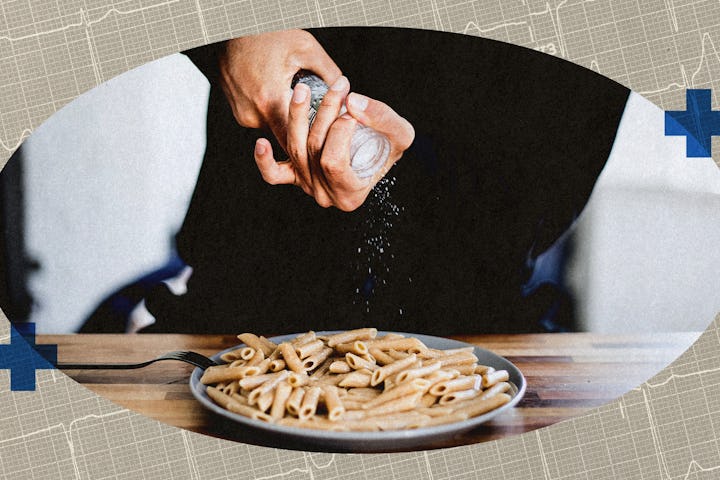 A person adding salt to a plate of pasta.