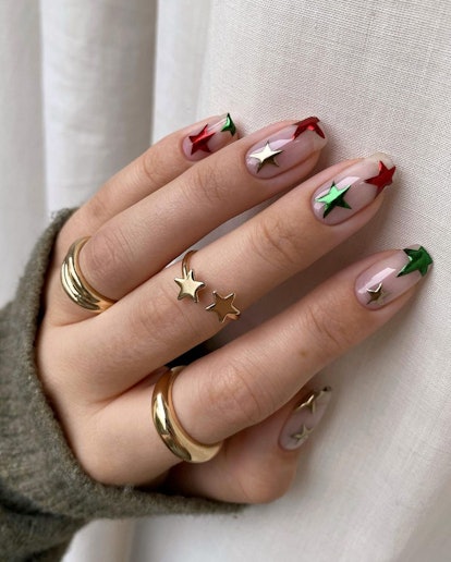 Clear nails with red, green, and silver chrome stars are a festive holiday nail design for Christmas...