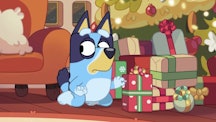 Bluey sneakily tries to peek at Christmas presents under the tree.