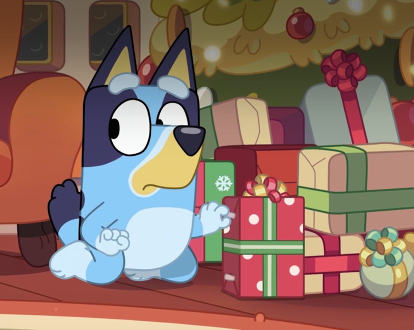 Bluey sneakily attempts to look at a present under the Christmas tree.