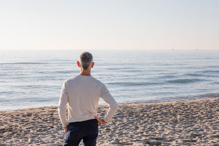 Man standing on a beach with his hand on his hip