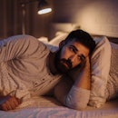 A man lying awake in bed who can't fall asleep.