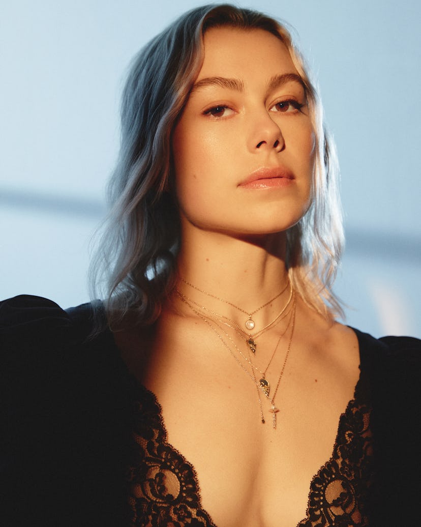 the musician Phoebe Bridgers wearing a black dress and three necklaces she designed with the jewelry...