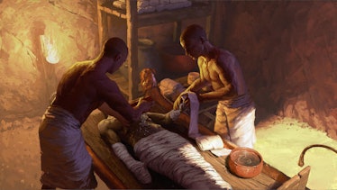 Two people lean over a body and prepare it with oils for burial in ancient Egypt