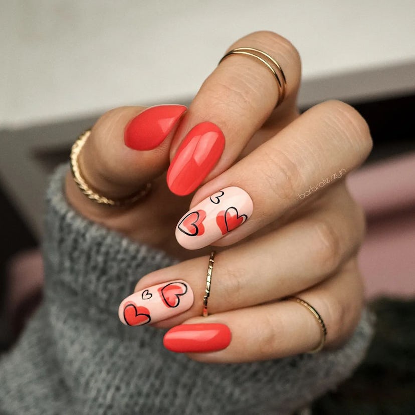 Red nail polish with accent nails is a simple heart nail art design for Valentine's Day 2023.