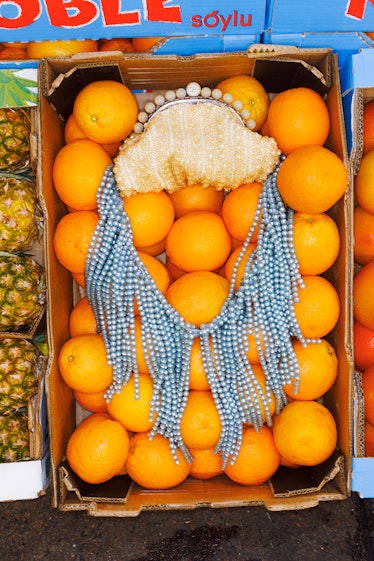 Gucci bag with pearls sitting in a box of oranges.