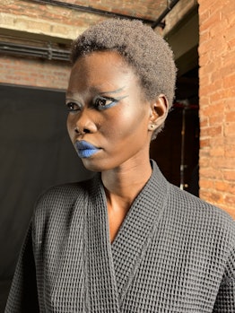 A model backstage at Rodarte F/W ‘23 wearing goth eyeliner and royal blue lipstick. 
