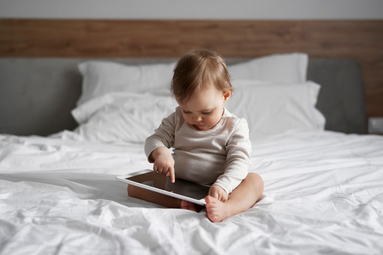A toddler using a tablet with a toddler learning video on it