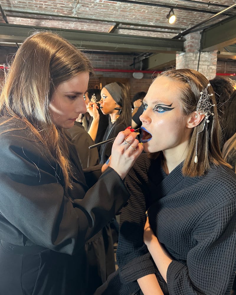A model getting their makeup done backstage at Rodarte F/W '23