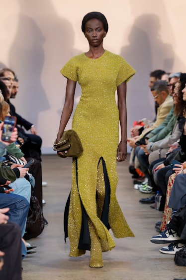 a model walks a runway wearing a gold dress