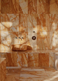 a hammam in a spa covered in amber-hued marble tiles