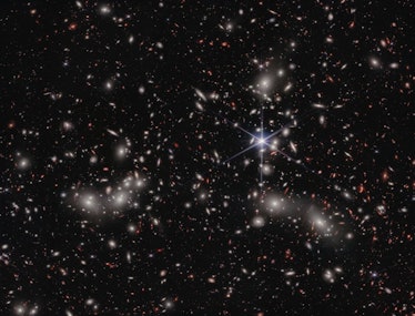color photo of a black sky, spangled with galaxies in various sizes, mostly small and yellow to red.