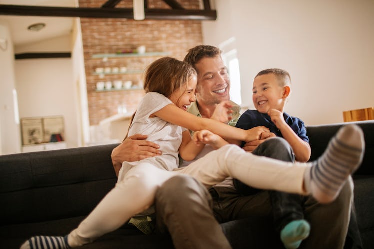 Happy man on couch playing with two kids