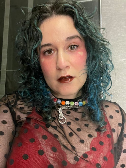 Woman with green hair wearing blush and dark brown lip gloss.